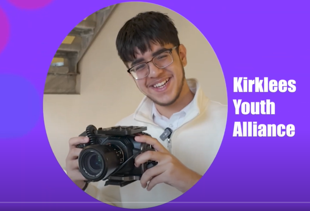 Man smiling with camera with the text Kirklees Youth Alliance